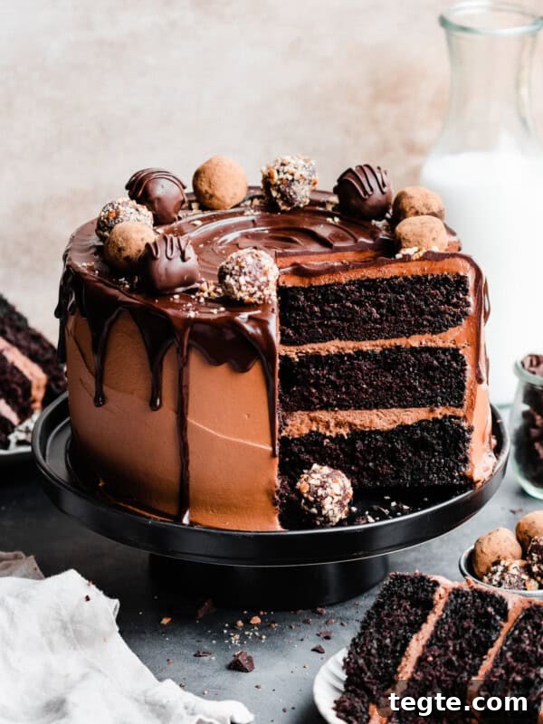 Eggless Chocolate Cake with Decadent Chocolate Fudge Frosting 12 The sliced chocolate truffle cake topped with chocolate drip and truffles, with slices on plates.