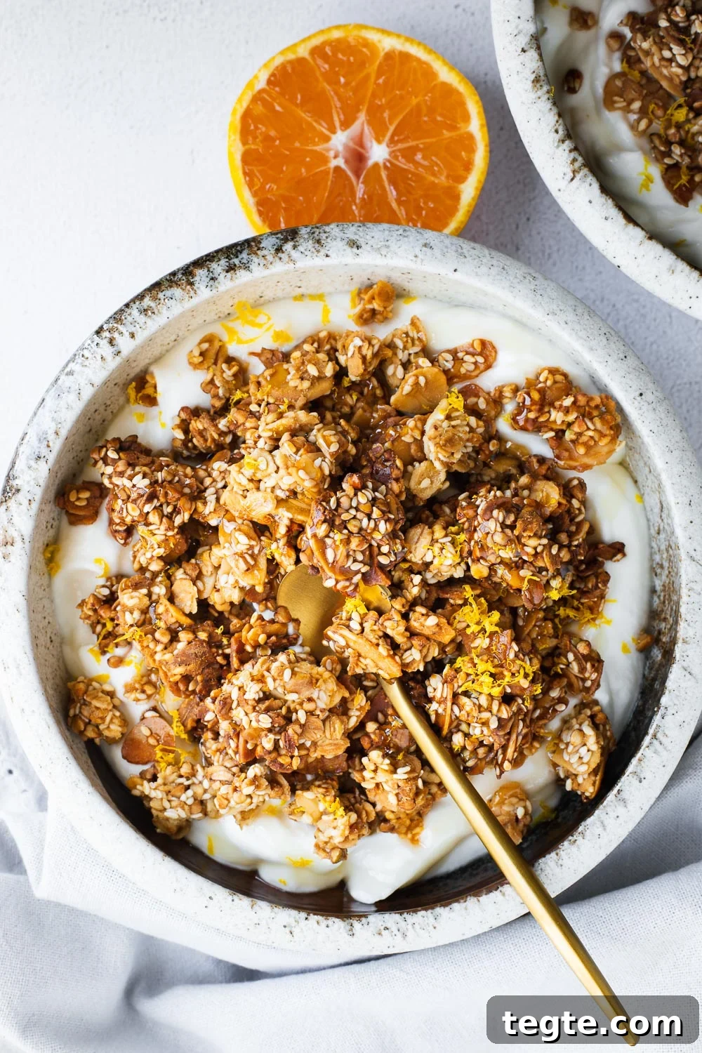 Homemade tahini granola with orange and honey, served in a bowl with yoghurt.