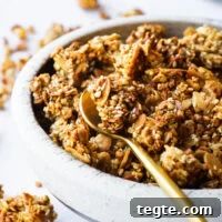 A close-up of a bowl of sesame tahini with granola served with a gold spoon.