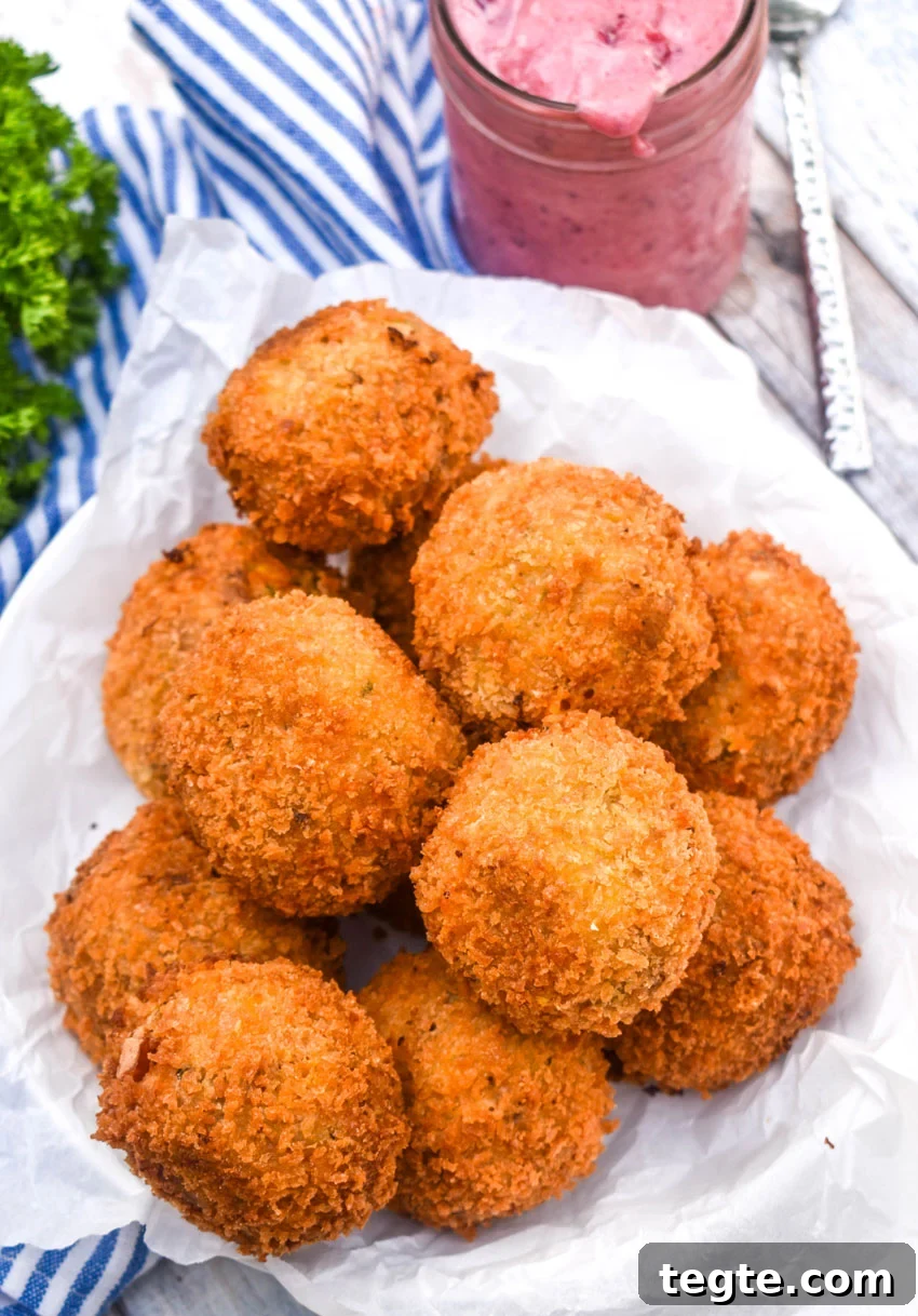 Cornbread Dressing Fritters Recipe: Crispy Southern Side Dish 3 a pile of crispy cornbread dressing fritters on a parchment paper lined bowl