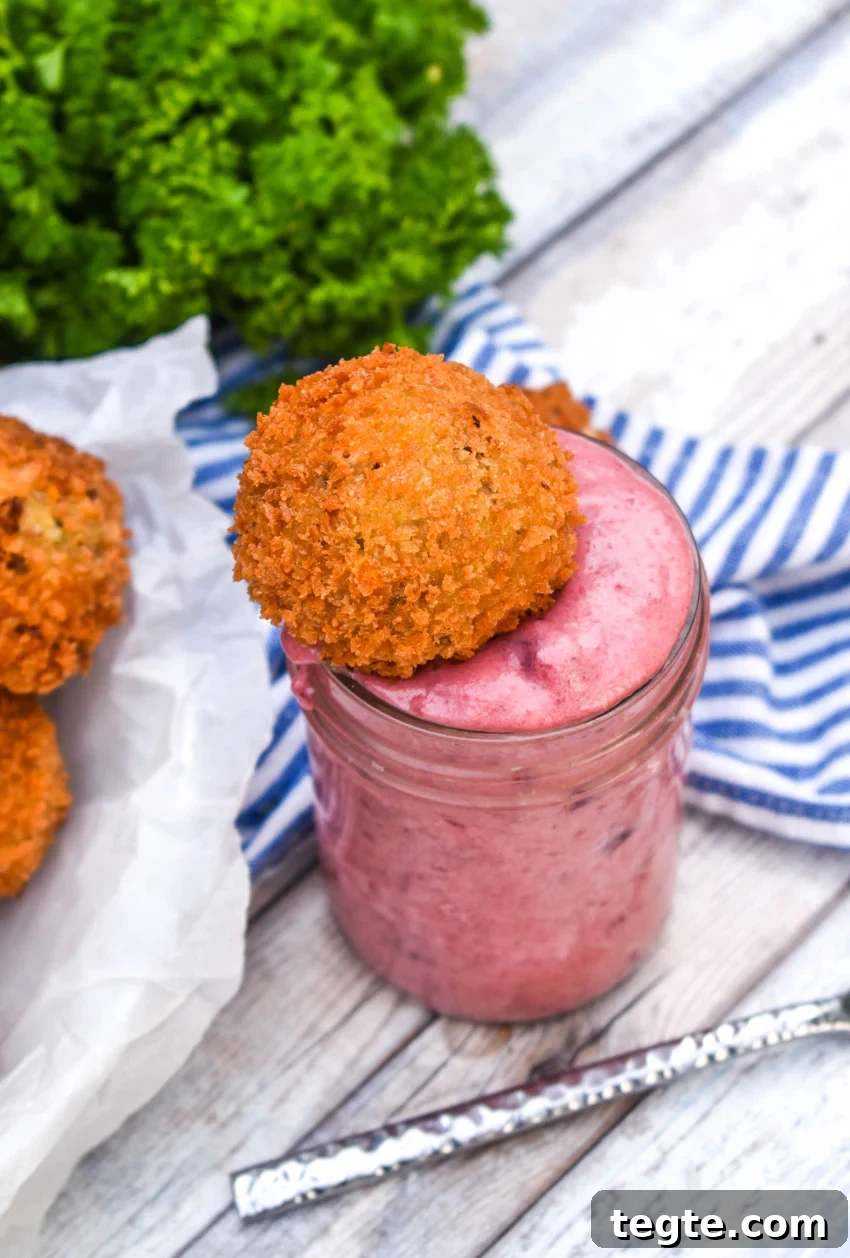 Cornbread Dressing Fritters Recipe: Crispy Southern Side Dish 6 a deep fried cornbread stuffing ball in a glass of cranberry dipping sauce