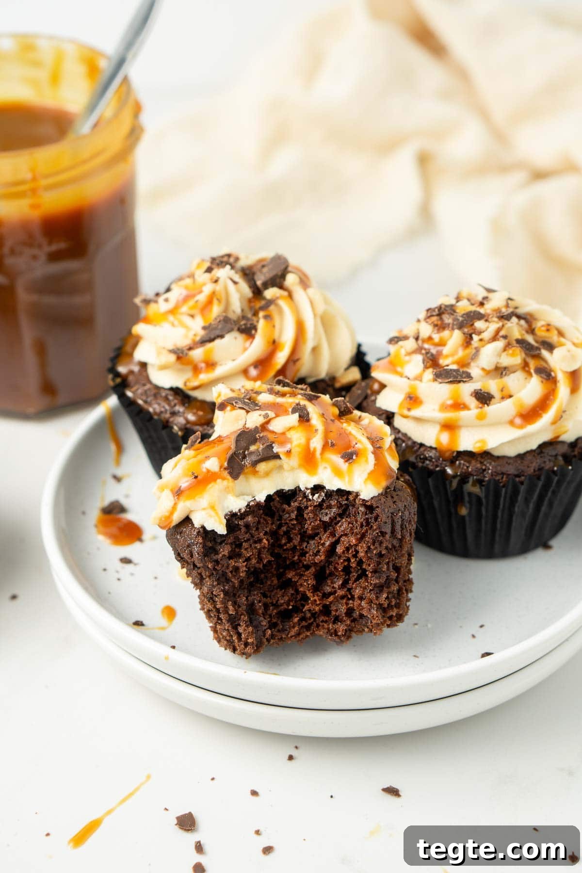Close up of vegan snickers cupcakes on a white plate with a bite taken.
