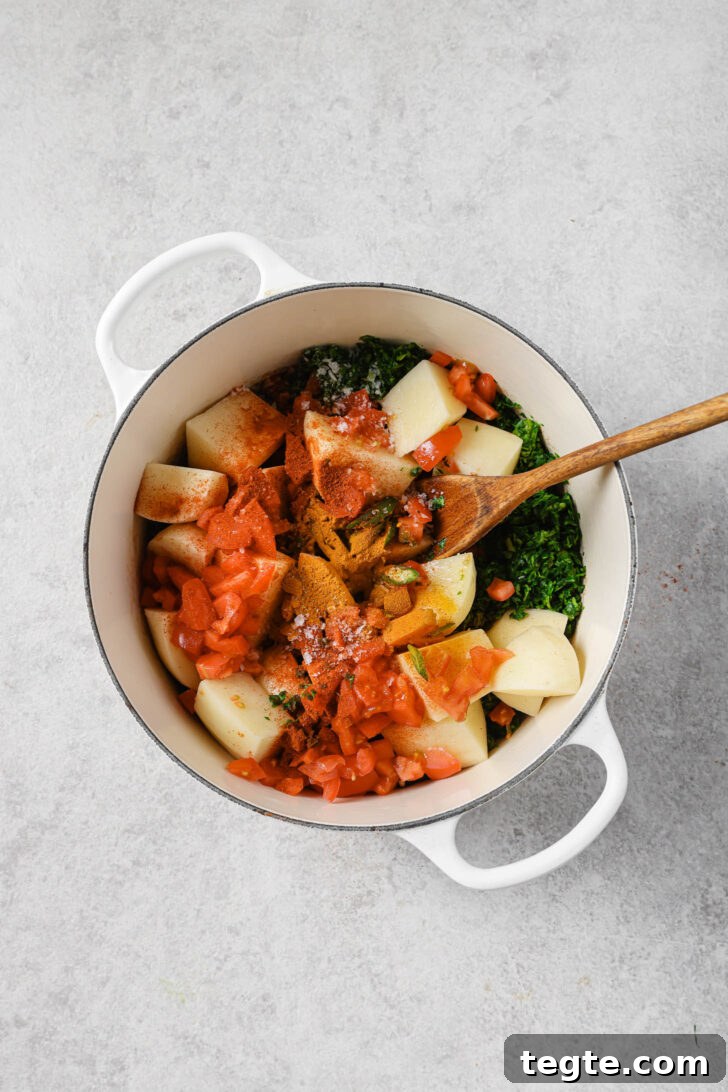 Potatoes, tomatoes, green chilli and spices added to pot with chopped fenugreek leaves.