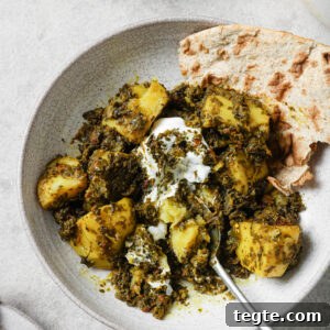 Partially eaten Aloo Methi in a plate with a dollop of yogurt and naan on the side.