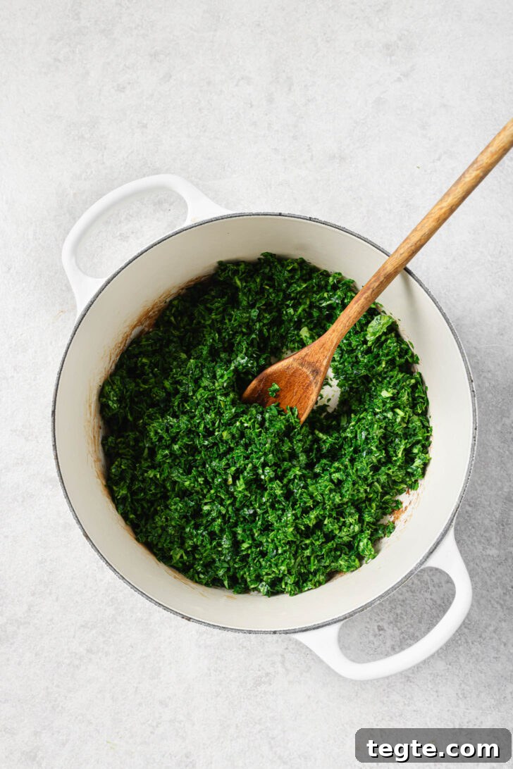Chopped fenugreek leaves in a dutch oven with a wooden spoon.