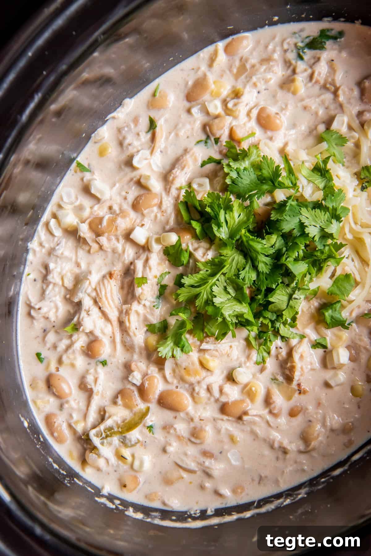 Creamy Crockpot Cream Cheese Chicken Chili Recipe 6 Cooked crock pot chicken chili in the crockpot with fresh cilantro leaves on top.