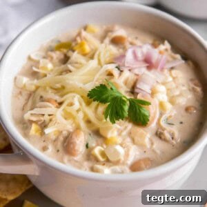 Creamy Crockpot Cream Cheese Chicken Chili Recipe 8 Crockpot Cream Cheese Chicken Chili in a bowl with cheese on top and chopped cilantro.