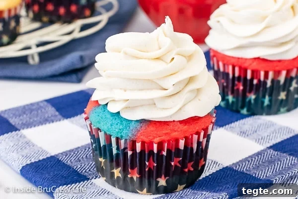 A cupcake topped with a swirl of vanilla buttercream on a blue and white towel.