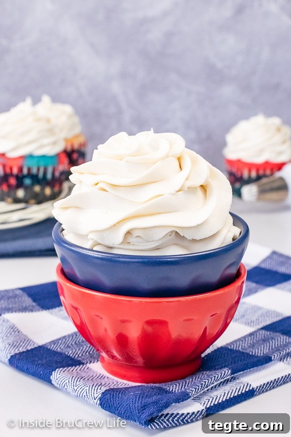 Two red and blue bowls stacked together with a swirl of vanilla buttercream frosting in it.