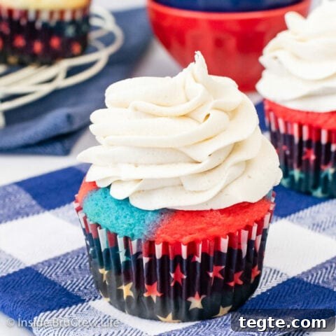 A blue and red cupcake topped with a swirl of vanilla frosting.