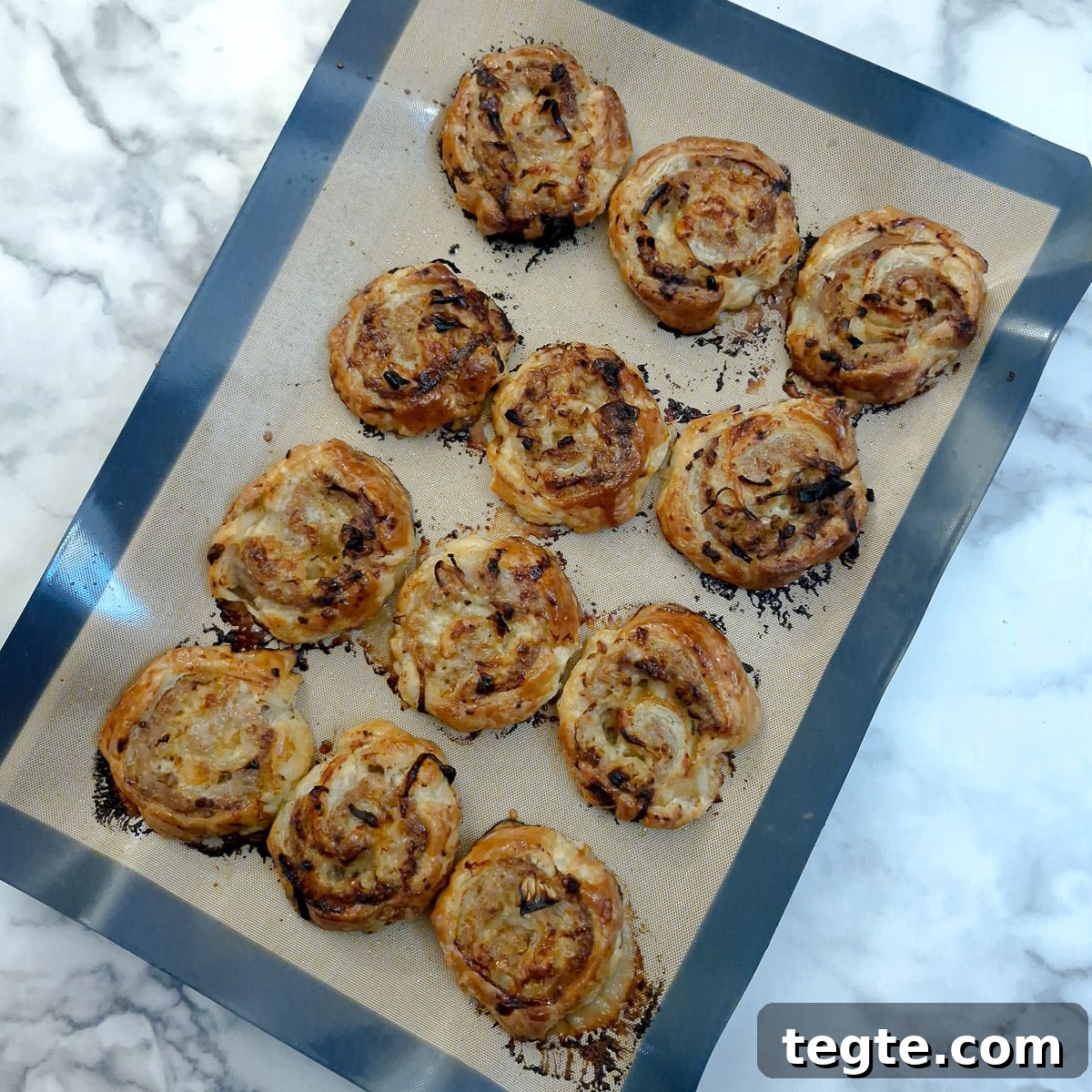 Savory Sausage and Caramelized Onion Pinwheel Appetizers 13 Baked sausage and onion pinwheels on a baking tray.