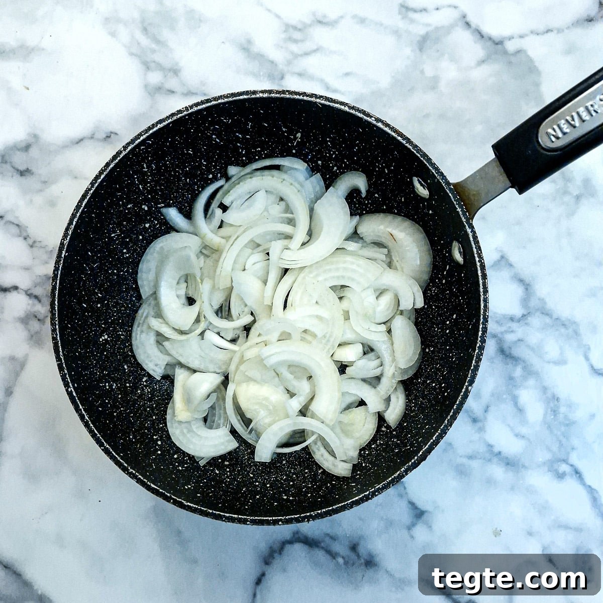 Savory Sausage and Caramelized Onion Pinwheel Appetizers 5 Raw sliced onions in a frying pan.