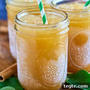 mason jar of frozen apple cider with green and white straw.