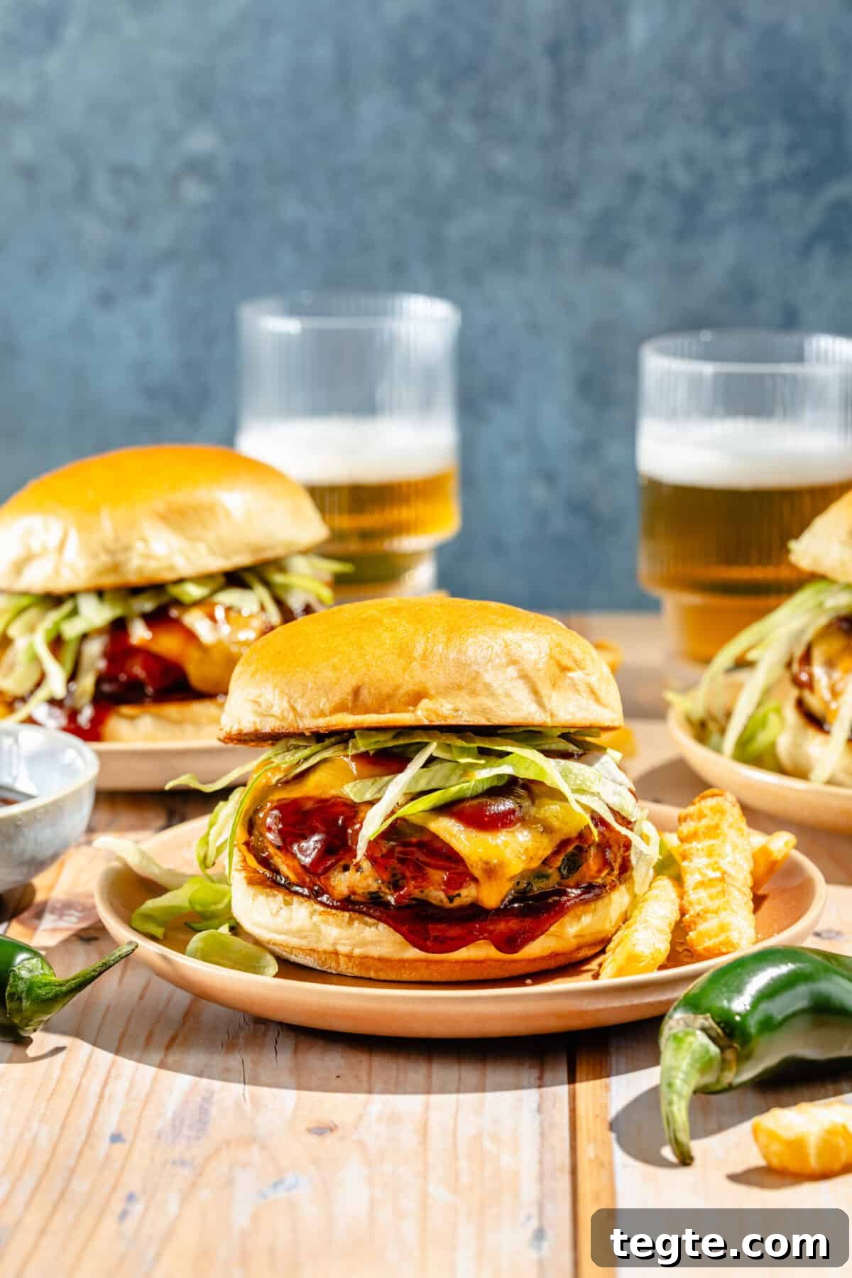 two jalapeno cheddar turkey burgers with beers in the background