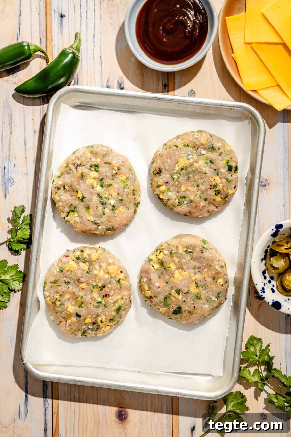 four uncooked turkey burgers with jalapeno peppers and cheddar cheese