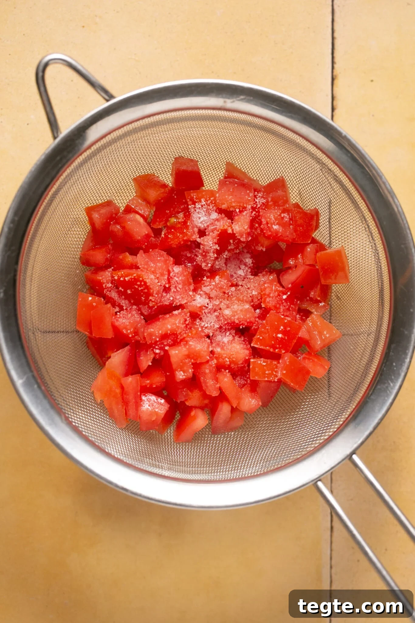 diced tomatoes in a strainer with salt on them