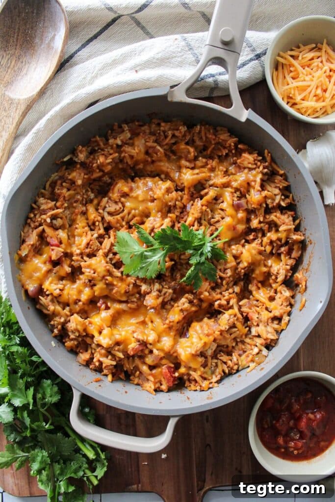Cheesy Taco Rice Skillet — One-Pan Weeknight Dinner 7 A skillet of cheesy taco rice garnished with cilantro.