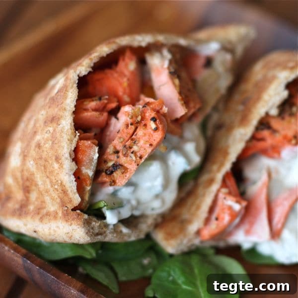 Healthy Broiled Salmon Gyros two pitas cut in half stuffed with broiled salmon and a white sauce with a side of spinach