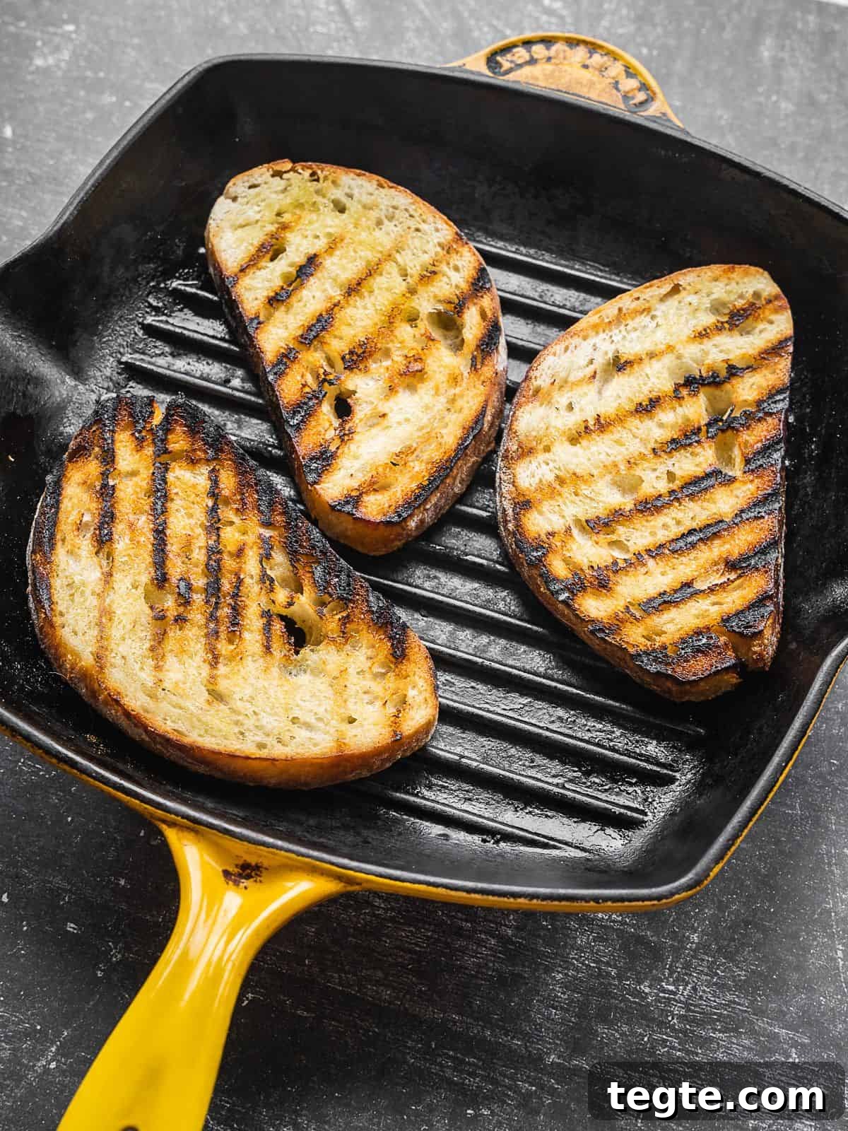 Creamy Burrata Bruschetta with Heirloom Tomatoes and Basil 5 Sliced bread toasting on a grill pan.