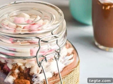 pickling jar filled with brown powder and marshamallows with two cups in the background