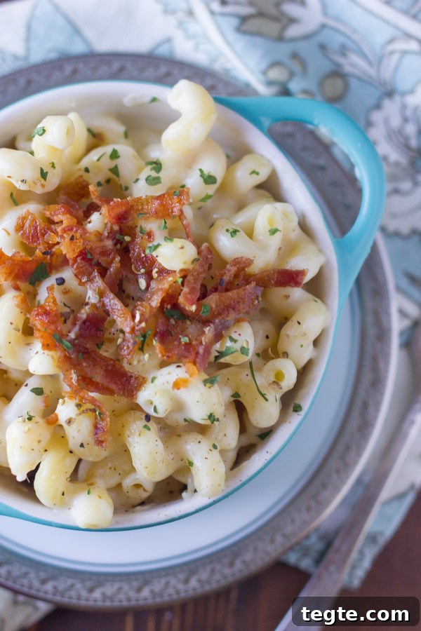 Creamy Mac and Cheese With Bacon in a bowl that is sitting on a plate.