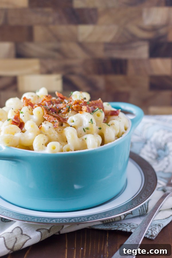 Creamy Mac and Cheese With Bacon in a bowl that is sitting on a plate.