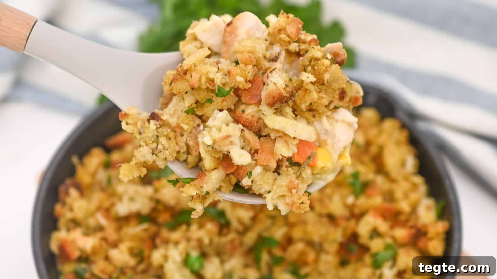 15 Creative Post-Thanksgiving Dinners to Transform Leftovers 3 A spoon lifting chicken and stuffing casserole from a cast iron skillet, with a striped towel in the background.