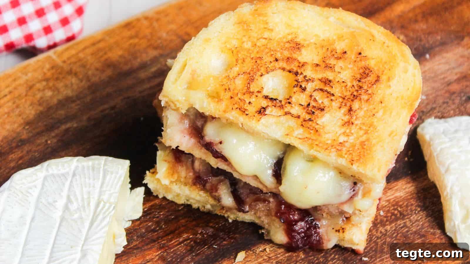 15 Creative Post-Thanksgiving Dinners to Transform Leftovers 7 Grilled cheese sandwich with melted cheese and cranberry sauce on a wooden board.
