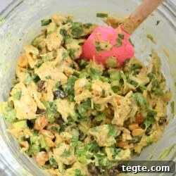 yellow chicken salad with pink spoon in mixing bowl