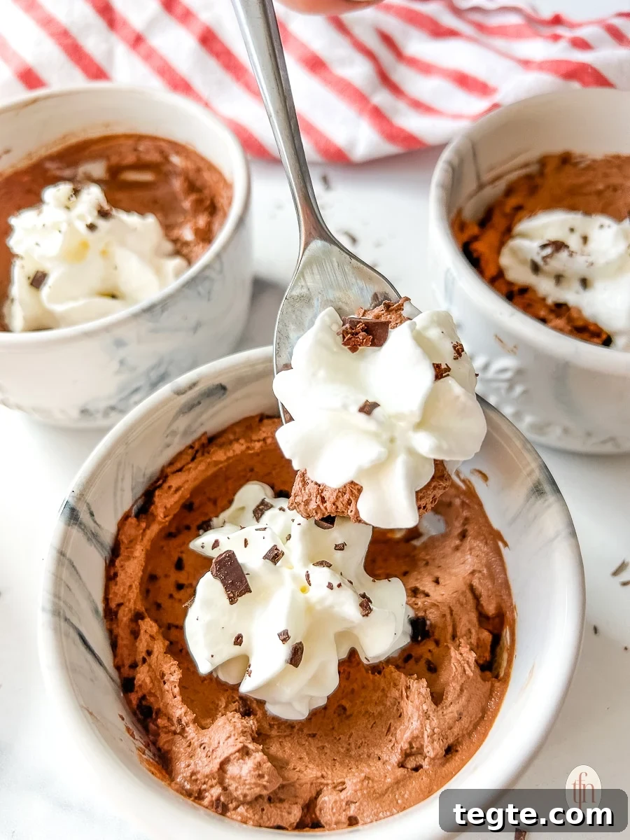 Decadent 3-Ingredient Chocolate Mousse Recipe 7 Spoon lifting whipped cream and mousse from a small bowl.