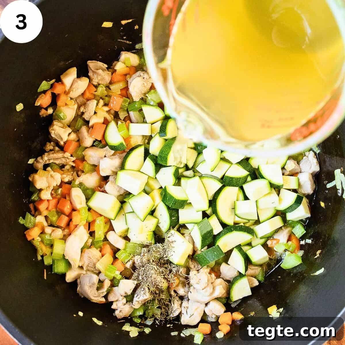 Hearty Homemade Chicken and Vegetable Soup Recipe 6 Pouring chicken broth into vegetables in a saucepan.