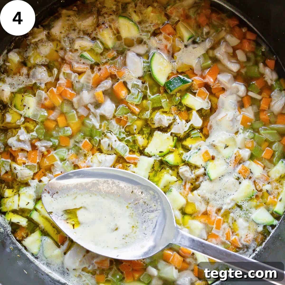 Hearty Homemade Chicken and Vegetable Soup Recipe 7 Skimming scum off soup with large spoon.