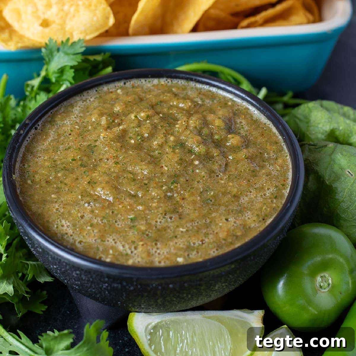 14 Pepper Recipes to Turn Up Flavor on Your Grill 14 Smoked salsa in a black bowl garnished with cilantro leaves and lime wedges, next to a blue platter with chips.