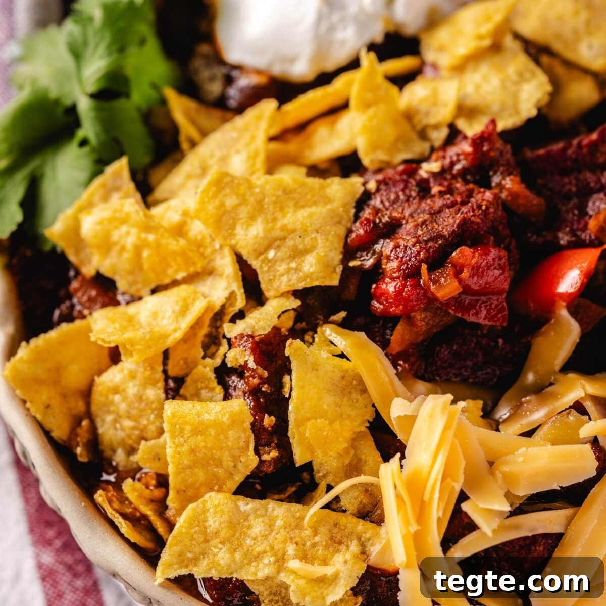 14 Pepper Recipes to Turn Up Flavor on Your Grill 8 A closeup shot of a bowl of chili topped with a dollop of sour cream and crumbled tortilla chips.
