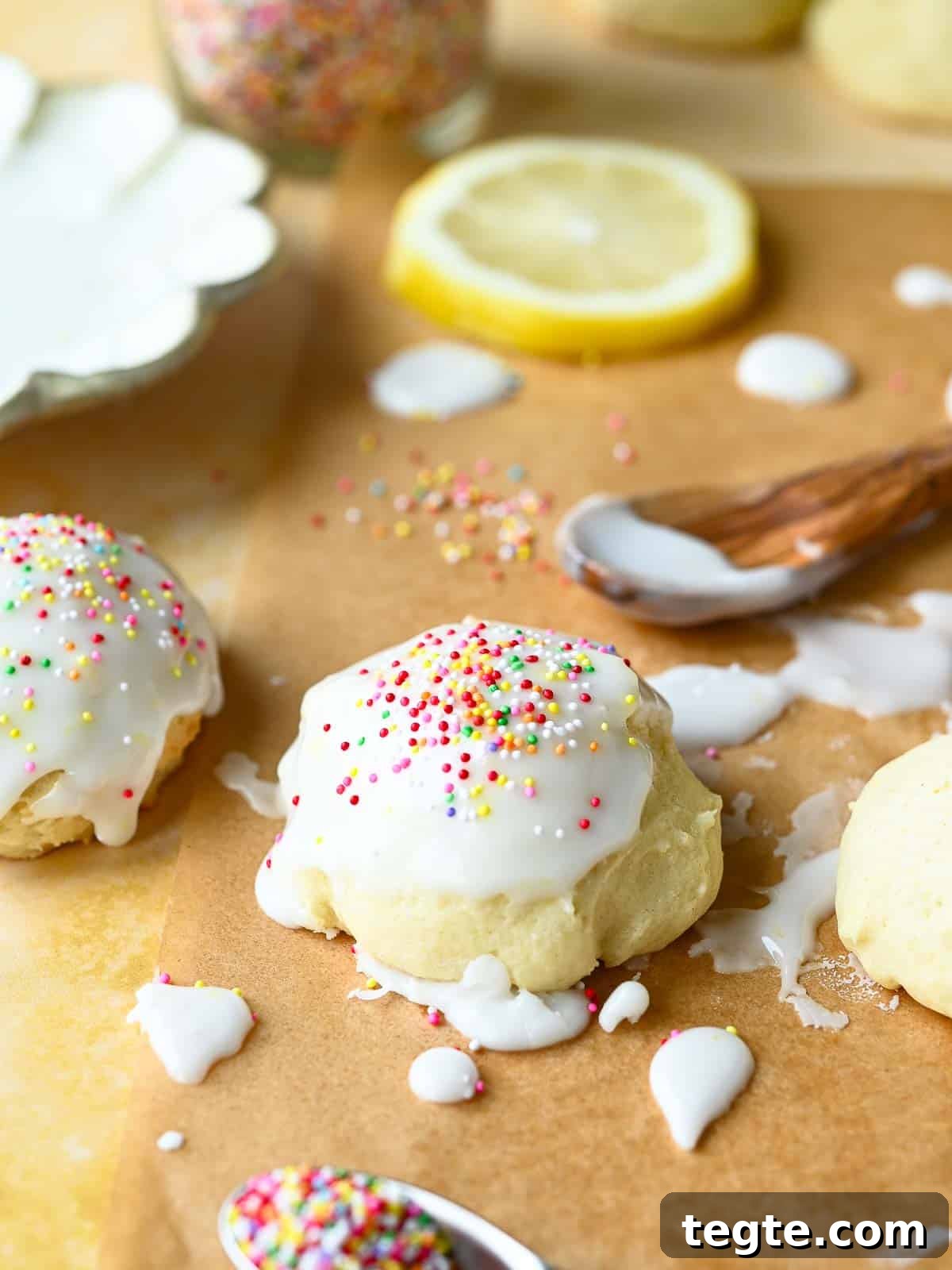 Italian Lemon Drop Cookies Recipe — Zesty Citrus Shortbread Tips 11 Italian lemon drop cookies with icing and sprinkles on parchment paper with lemons and sprinkles in the background.