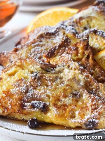 Panettone French toast on a beige platter with orange slices.