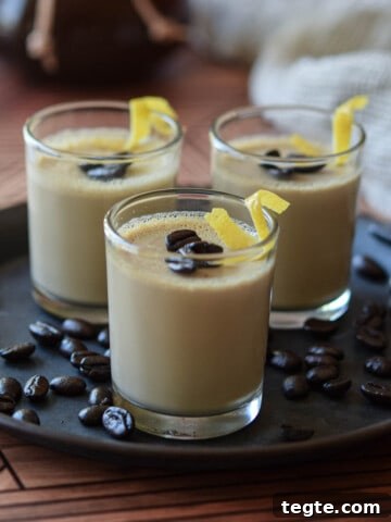 Espresso panna cotta in small glass jars topped with coffee beans and lemon rind.