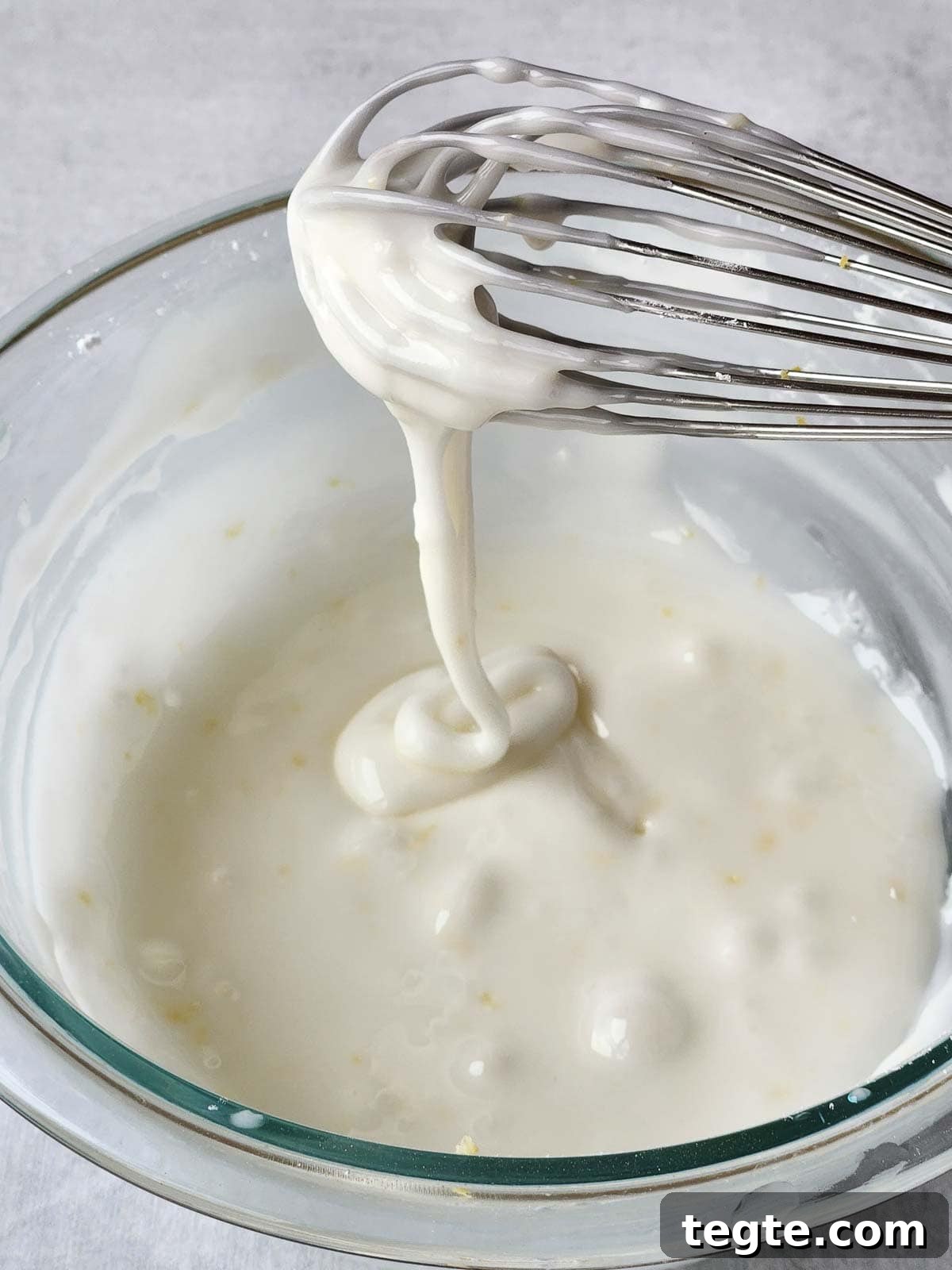 Italian Lemon Drop Cookies Recipe — Zesty Citrus Shortbread Tips 9 White icing dripping off a whisk into a bowl.
