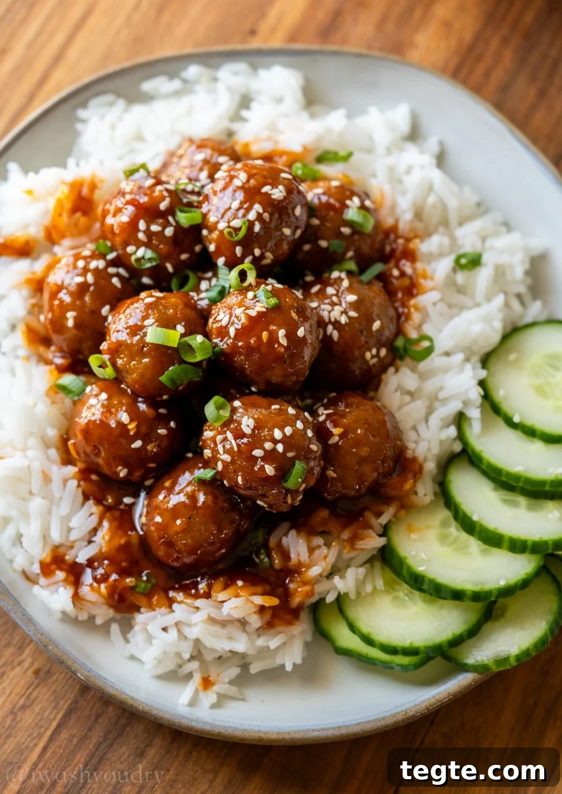 Korean BBQ Meatballs over a bed of white rice with sliced cucumbers.