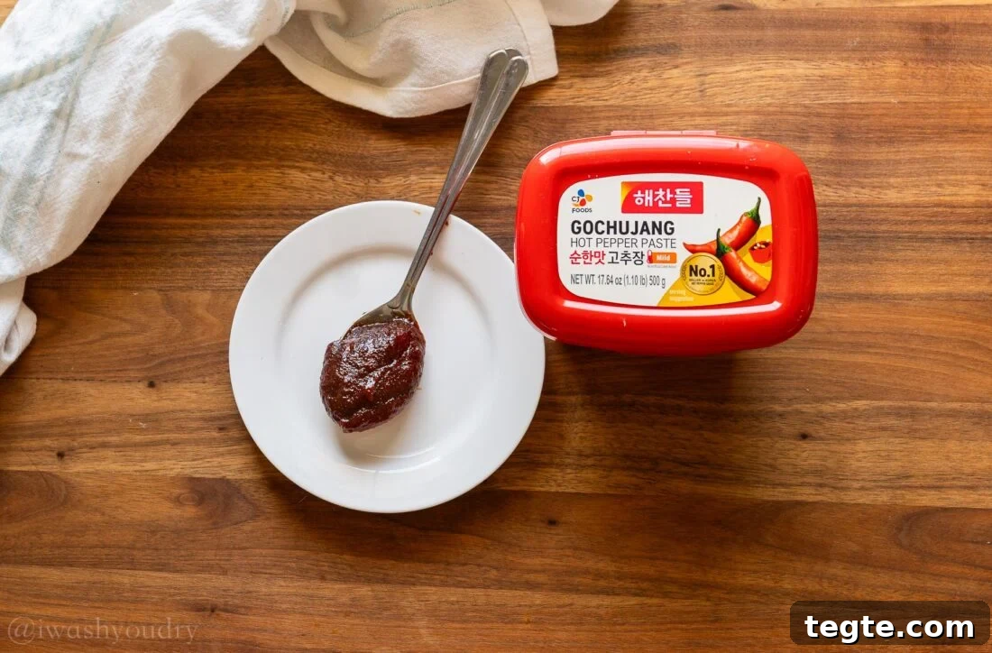 gochujang paste on white plate with red tub next to it.