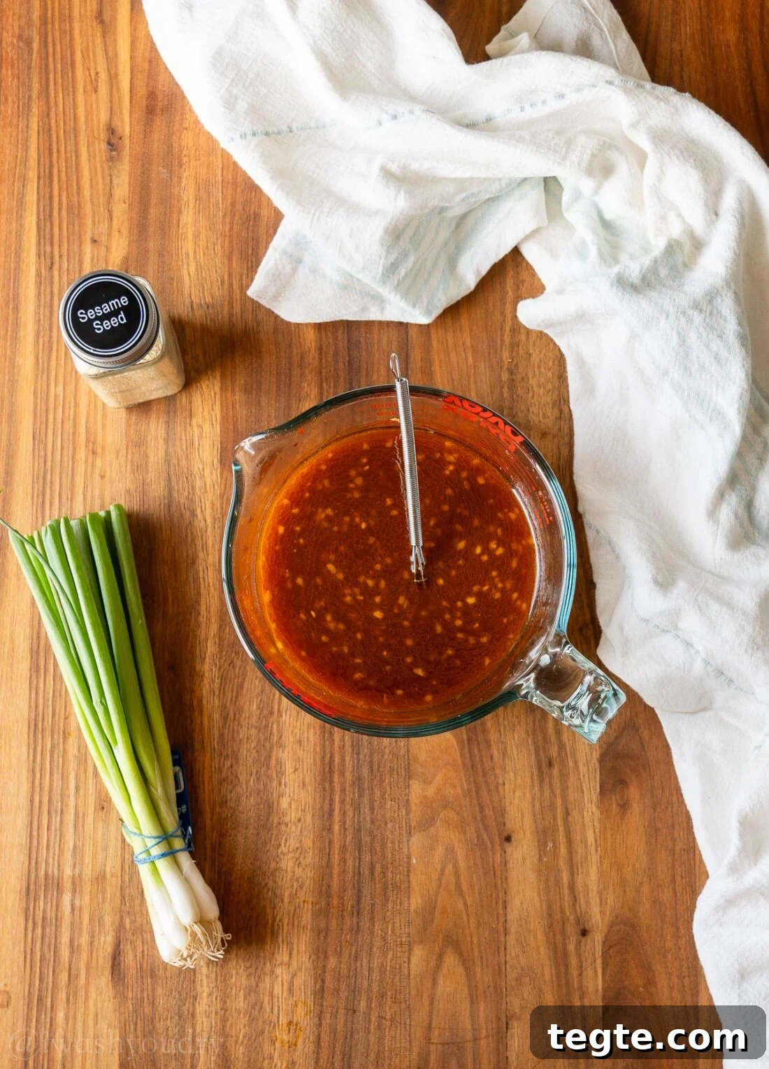Korean BBQ Sauce ingredients in a measuring cup on wooden surface with green onions.