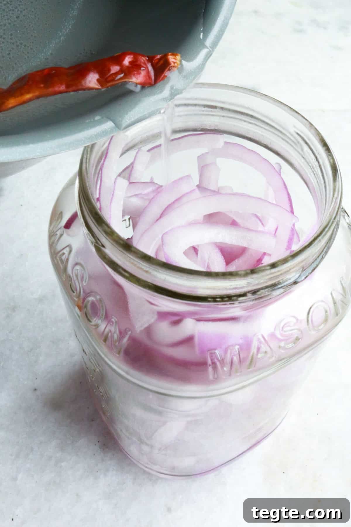 Pouring brine into a jar of red onions