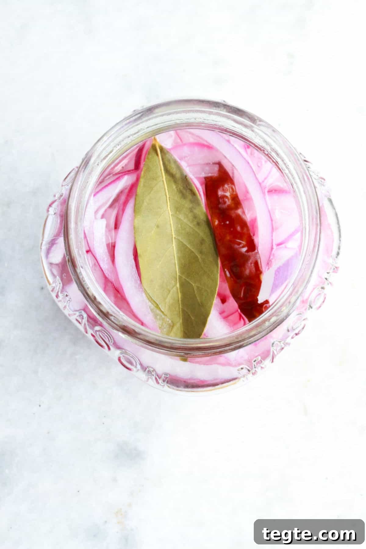 jar of pickled red onions with chile de arbol and bay leaf