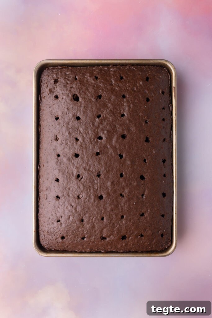 Chocolate cake fresh out of the oven with holes poked into the top with a straw.