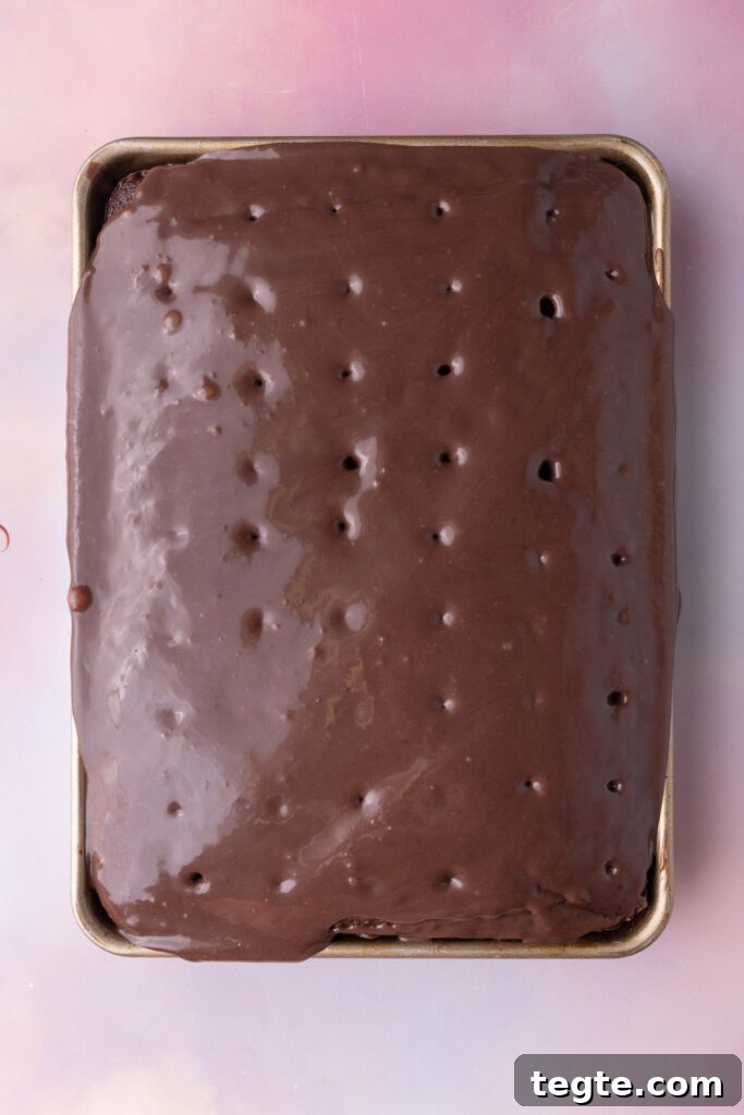 Chocolate and condensed milk mixture sinking into holes poked in a chocolate cake. 