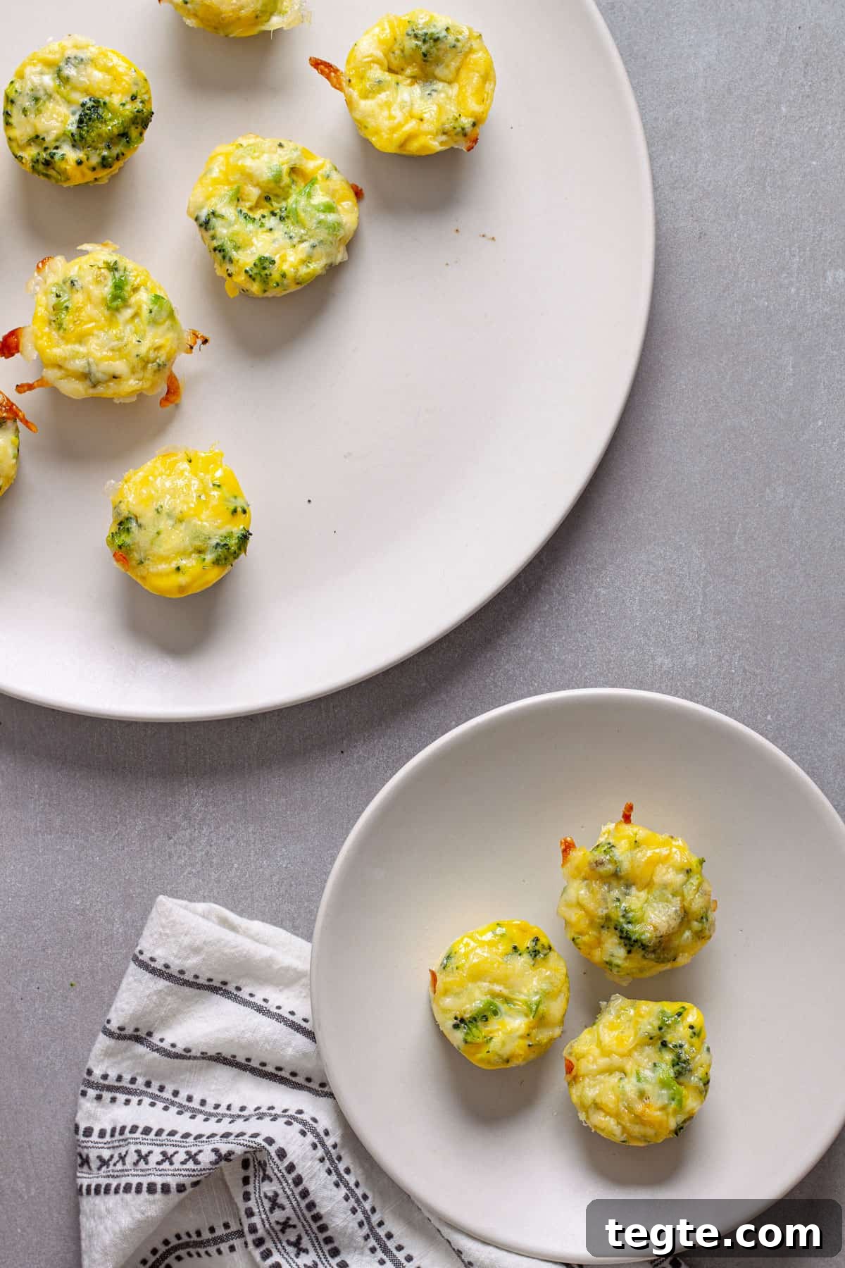 A serving of mini egg bites on a small plate with a platter of more egg bites in the background.