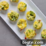 A tray of mini broccoli and cheddar egg bites on a gray table.