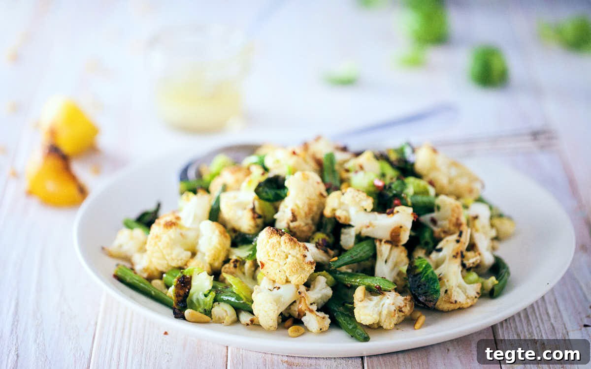 Side view of roasted cauliflow and brussels sprout salad on a white wooden background