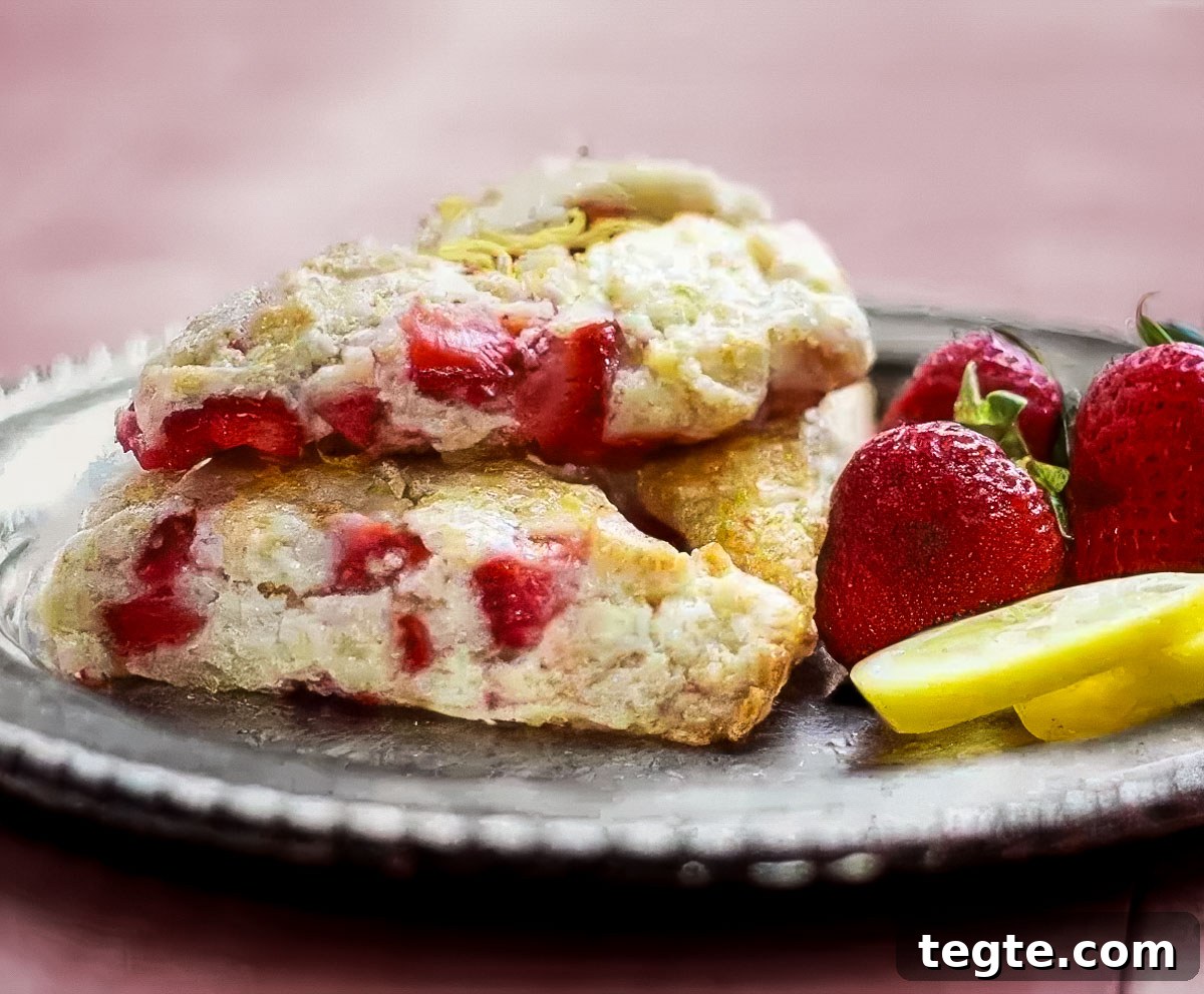 Strawberry Lemon Scones Recipe — Light, Flaky & Zesty 2 a vintage plate holds three strawberry lemon scones and a few fresh strawberries and lemon slices