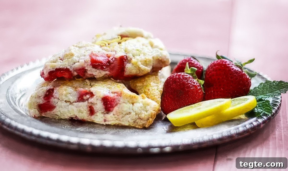 Strawberry Lemon Scones Recipe — Light, Flaky & Zesty 5 a vintage plate holds three strawberry lemon scones and a few fresh strawberries and lemon slices
